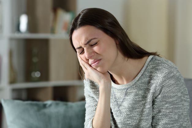 woman holding cheek because of tooth abscess